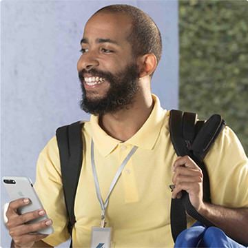 Rapaz saindo com mochila nas costas, sorrindo e celular na mão